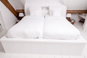 Het tweepersoonsbed is gedekt bed fris wit katoenen beddengoed Foto (c) Joop Grootenboer